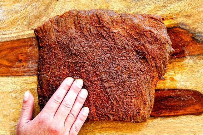 showing how to make carne asada by rubbing flank steak with wet rub