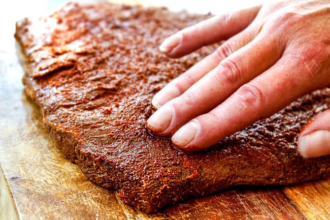 showing how to make street tacos by massaging a rub all over steak