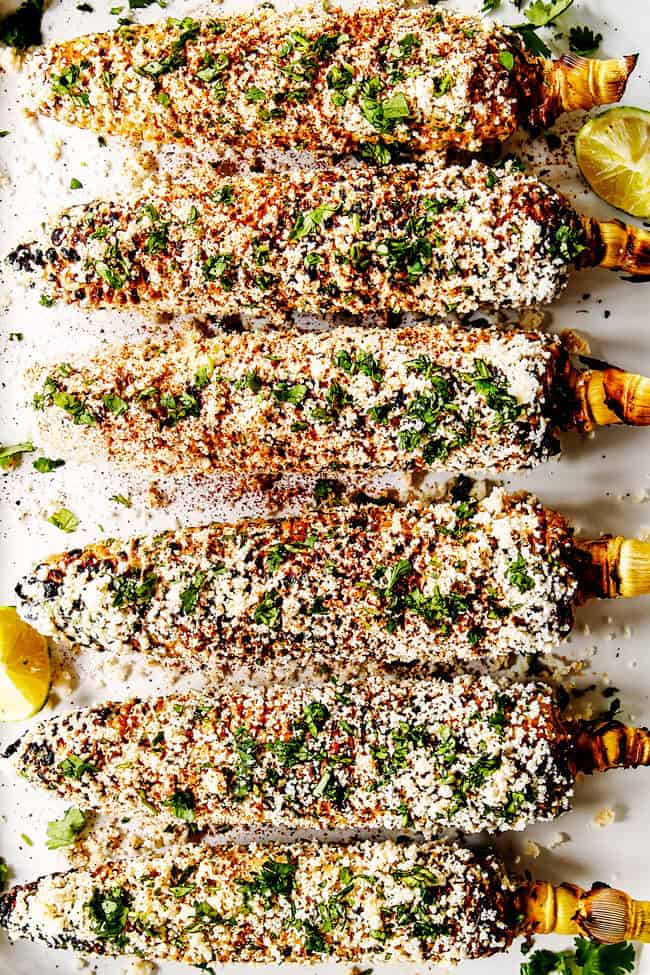 top view of elotes mexicanos with mayonnaise, sour cream, cilantro, lime and cotija cheese