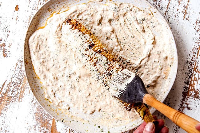 showing how to make elote by smothering in mayonnaise cream sauce