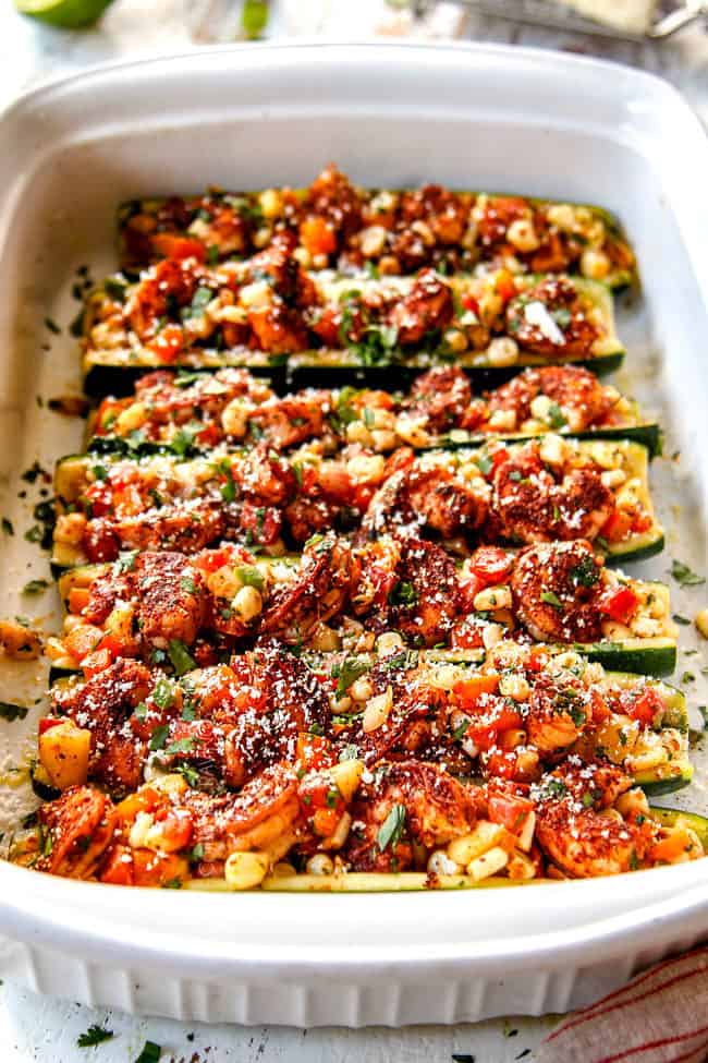 baked zucchini boats lined n a row in a 9x13 baking dish