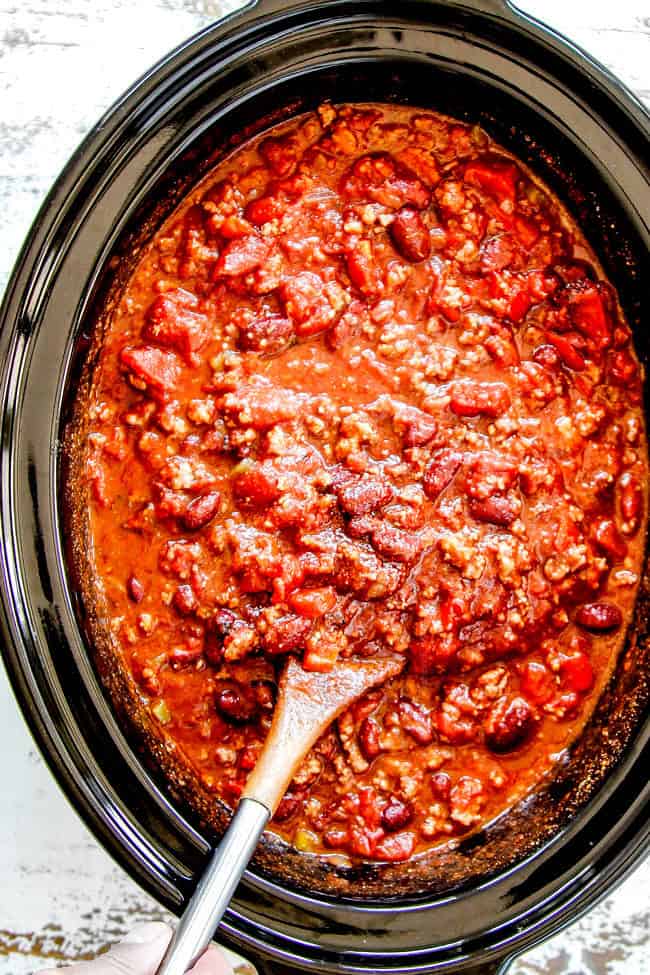 showing how to make crockpot chili recipe by stirring chili in the slow cooker
