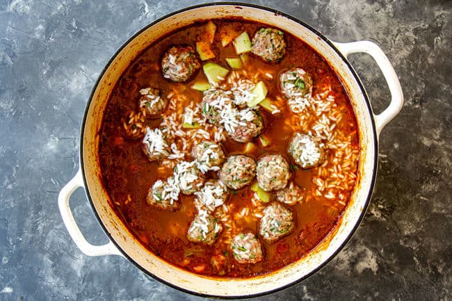 showing how to make Albondigas Soup by adding meatballs to soup to simmer