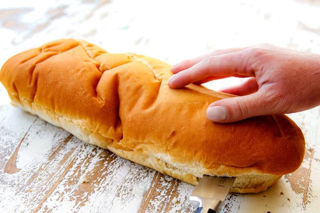 showing how to make garlic bread by slicing French Bread in half lengthwise