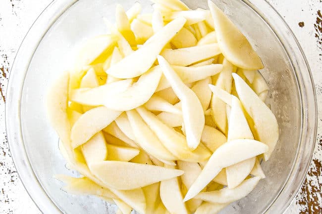 showing how to make Pear Pie by tossing pear slices with lemon juice