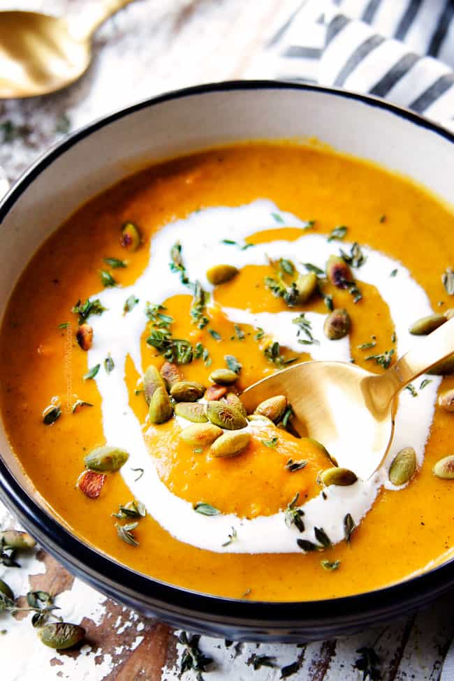 showing how healthy the butternut squash soup is by dipping a spoon into the soup