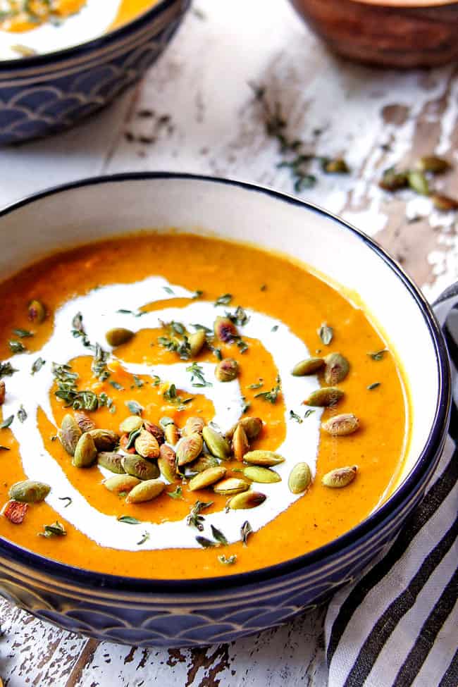 showing how to serve creamy butternut squash soup by garnishing with pepitas