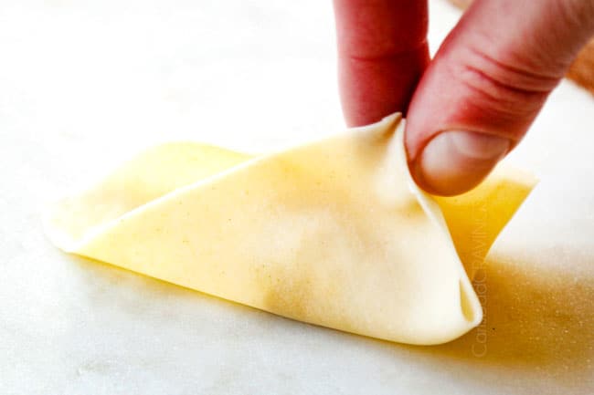 showing how to make homemade crab rangoon by folding three corners up together 