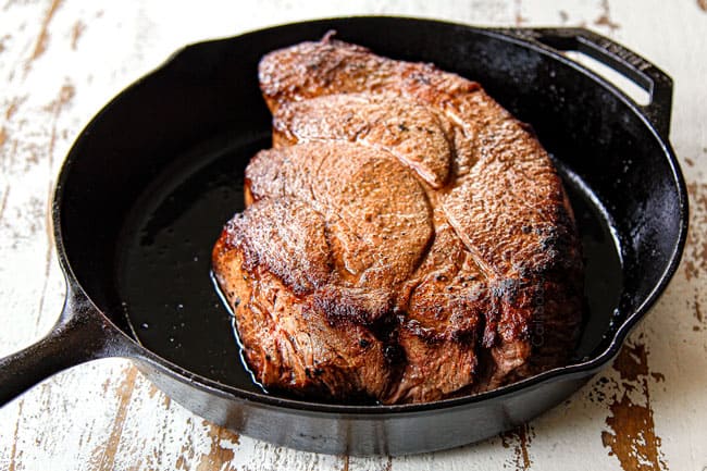 showing how to make oven pot roast recipe by searing the roast in a cast iron skillet