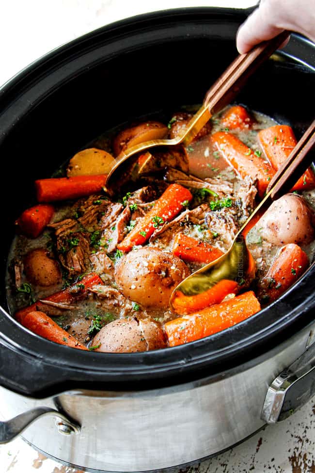 showing how to cook a roast in a crock pot by stirring carrot and potatoes in the crockpot