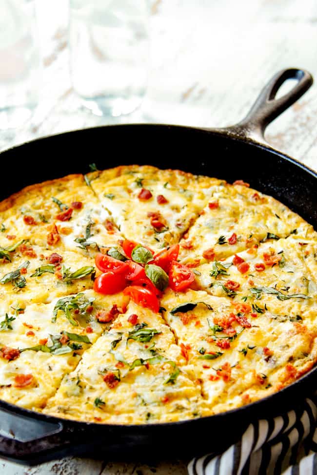 showing how to serve oven frittata recipe by topping it with tomatoes and fresh basil 