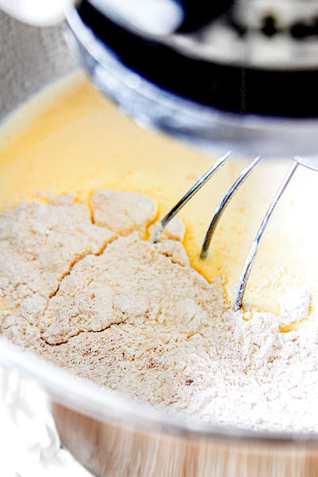 showing how to make authentic tres leches cake by adding flour in thirds into wet ingredients