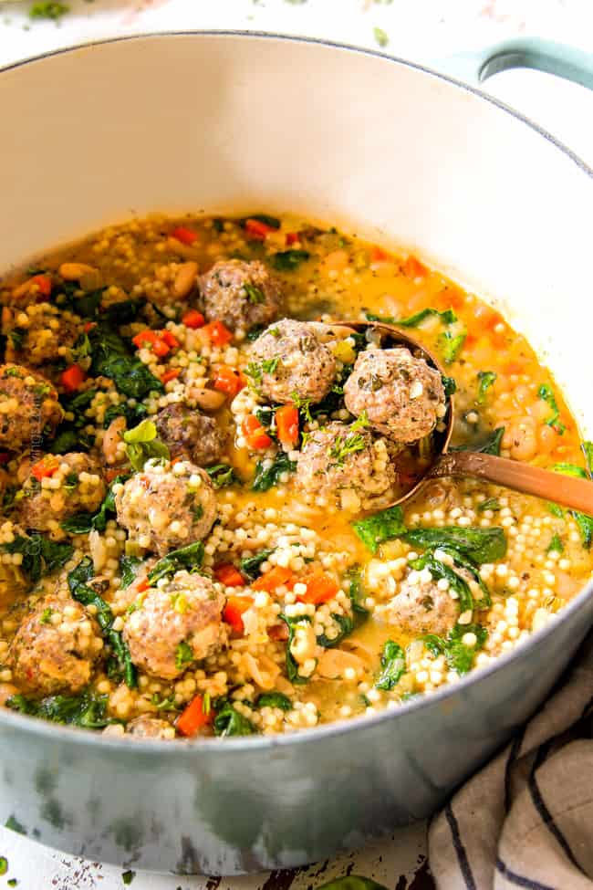 showing how to serve easy Italian Meatball Soup recipe by  scooping a big spoonful of soup in a brass ladle