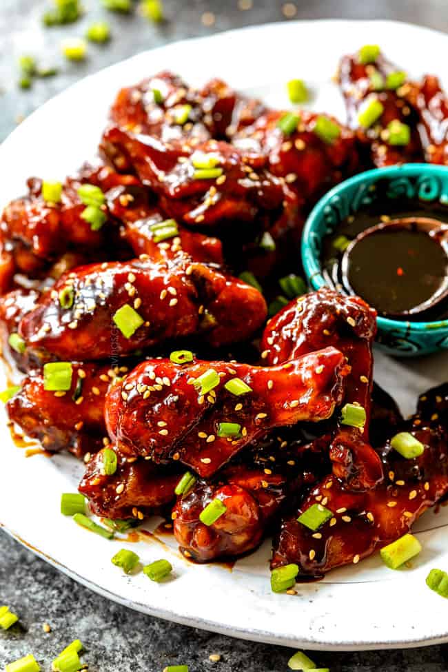 Korean Chicken Wings lined on a white platter with sesame seeds and green onions ready to serve