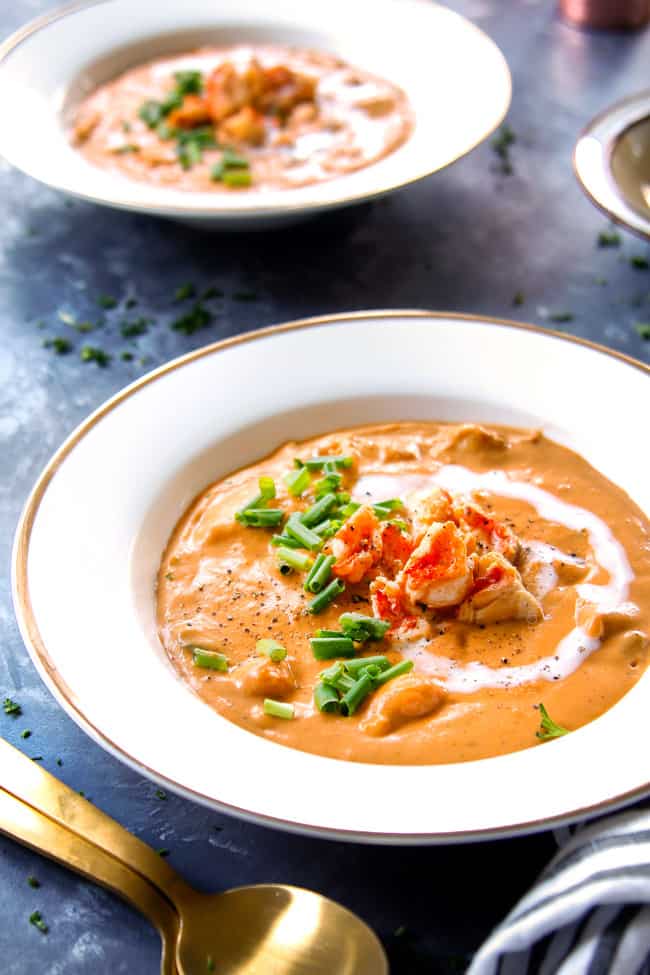 a bowl of  lobster bisque soup garnished with heavy cream lobster and chives