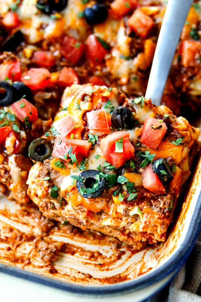 up close of a slice of Mexican lasagna with noodles being scooped out of the pan 