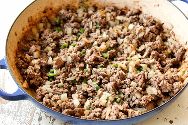 showing how to make Picadillo recipe by browning ground beef with onions and jalapenos in a large pot