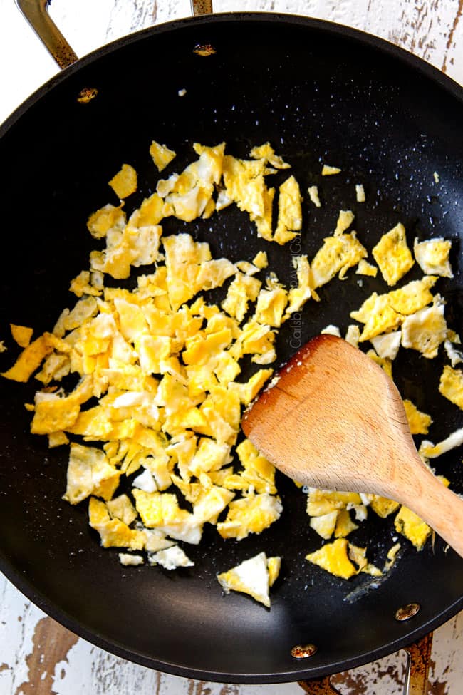 showing how to make Singapore Noodles by chopping up eggs in the skillet