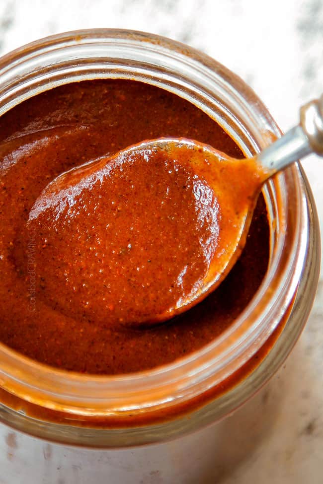 showing the correct consistency of enchilada sauce recipe by coating a spoon