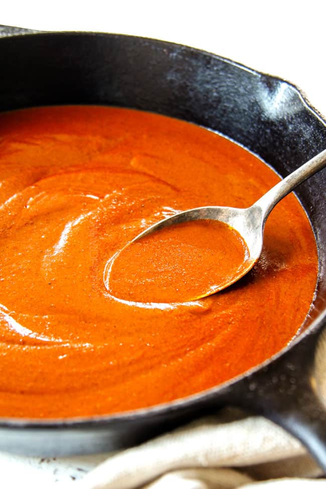 showing how to make homemade enchilada sauce recipe by stirring in a large cast iron skillet