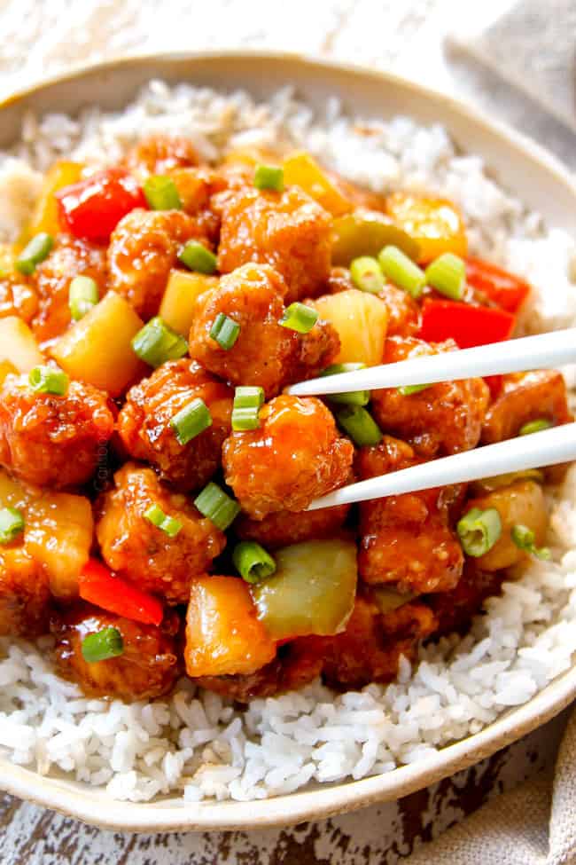 showing how to eat Sweet and Sour Chicken recipe by picking up chicken with chopsticks