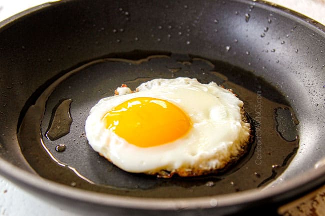 showing how to make huevos rancheros recipe by frying an egg in a nonstick skillet until the whites are set and the yolk is runny