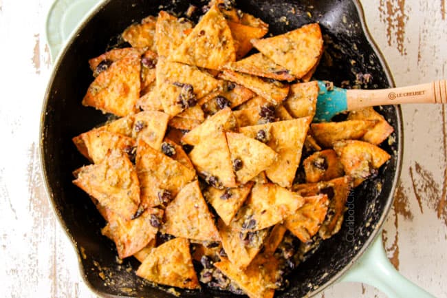 showing how to make Chilaquiles Verdes by stirring tortilla chips with salsa verde