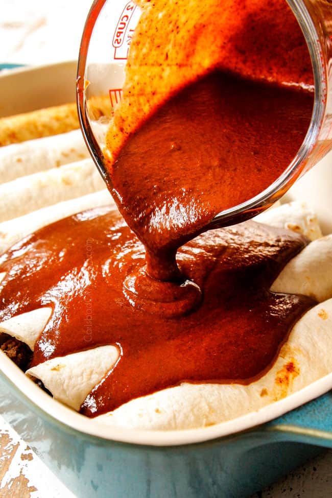showing how to beef enchiladas by pouring enchilada sauce over rolled tortillas