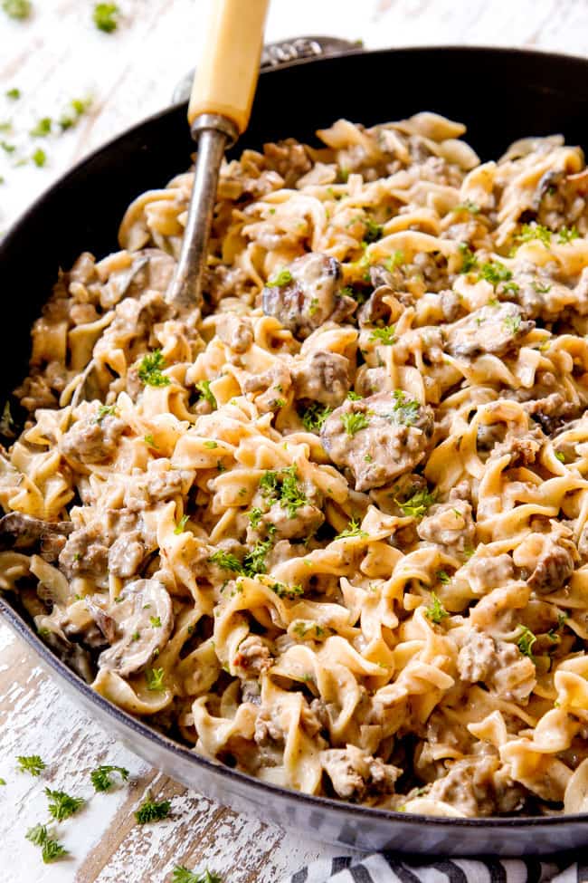 showing how to serve best ground beef stroganoff recipe by garnishing with parsley in a skillet 