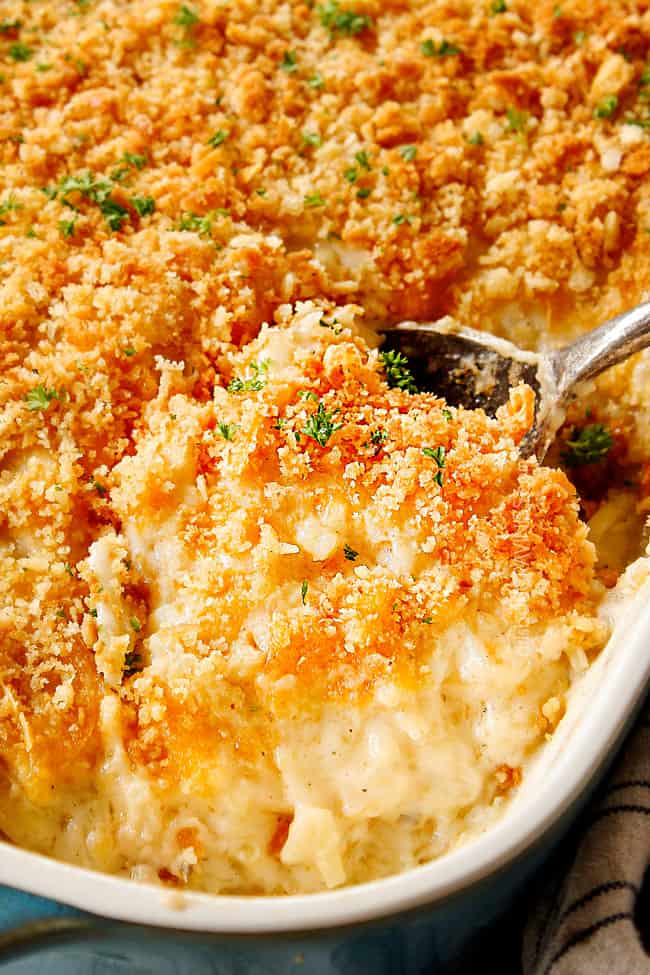 up close of a scoop of cheesy hashbrown casserole with Ritz cracker topping showing how creamy it ts