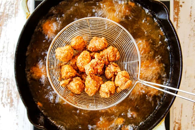 showing how to make KFC Popcorn Chicken by frying chicken until  golden them removing with  a strainer