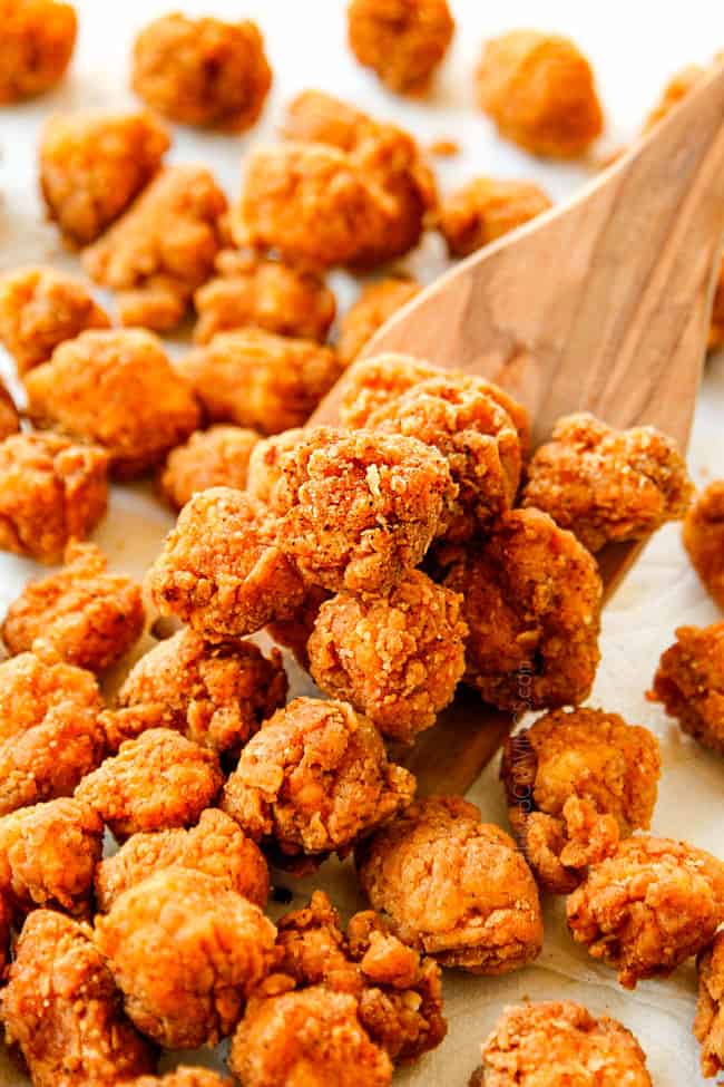 showing how to make KFC  Popcorn Chicken recipe by scooping up chicken from draining on paper towels 