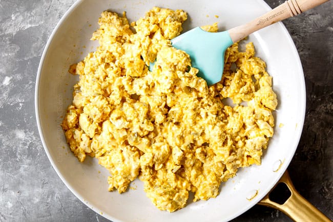 showing how to make breakfast tacos by cooking scrambled eggs with cheese and green chilies