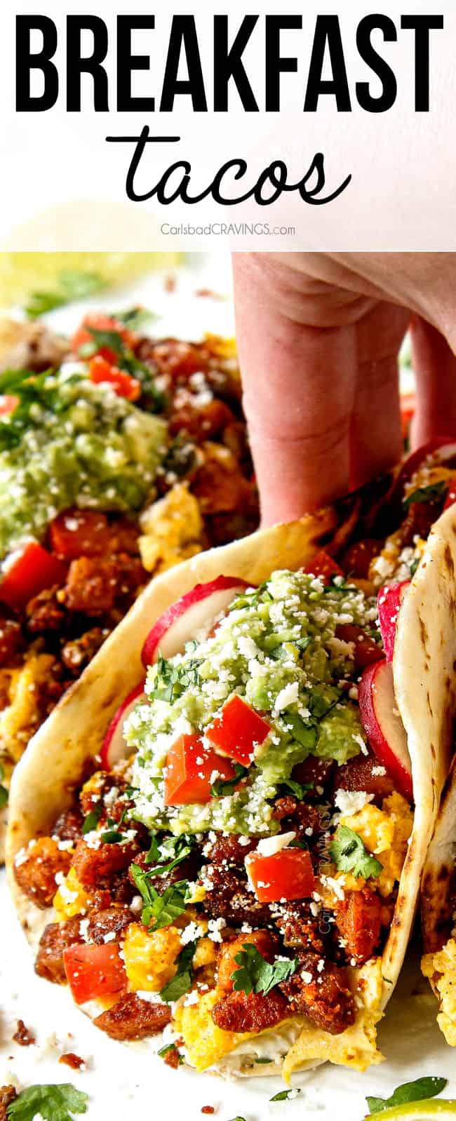 up close of a hand holding a breakfast taco showing the ingredients - potatoes, eggs, chorizo, guacamole