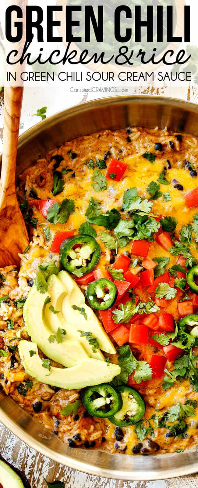 top view of Green Chili Chicken in a stainless steel skillet topped with tomatoes, avocado and cilantro showing how cheesy it is