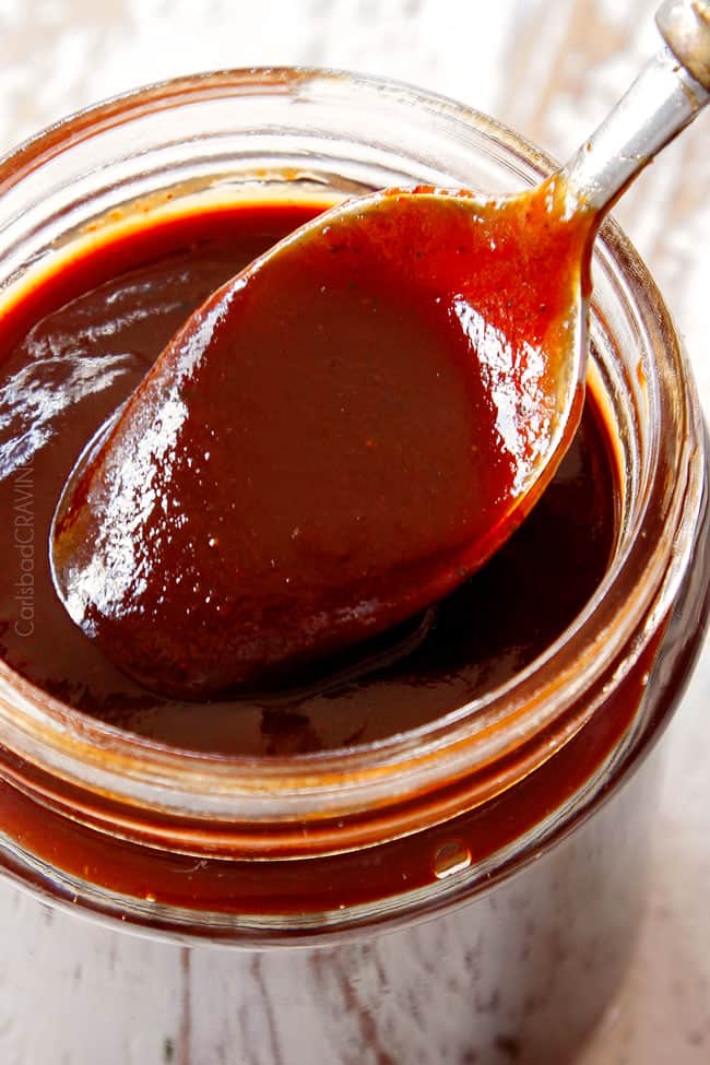 showing how to make BBQ burger recipe by dipping a spoon into the best homemade BBQ sauce