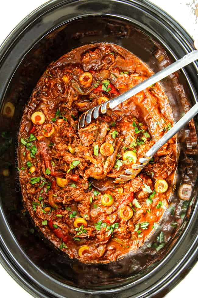 showing how to make Cuban Ropa Vieja by soaking shredded beef in juices in the crockpot