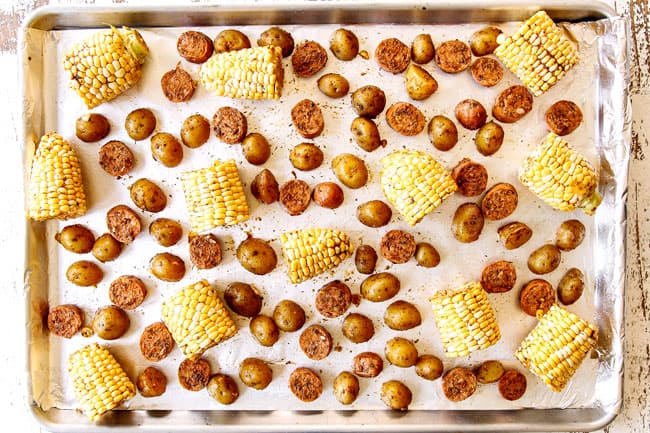 showing how to make easy shrimp boil recipe by lining corn, potatoes and sausage on a large baking sheet