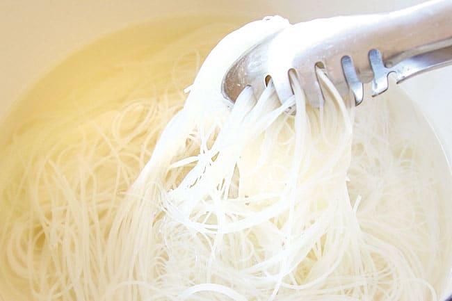 showing how to make rice noodles by soaking rice noodles in hot water until tender