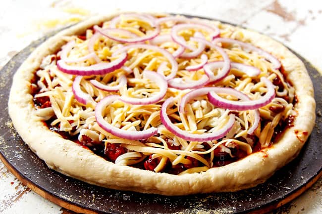 showing how to make BBQ Chicken Pizza recipe by topping cheese with red onions