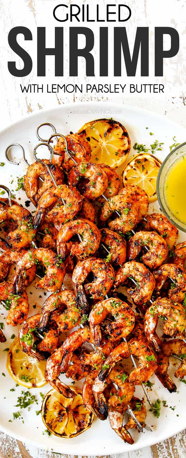 top view of grilled shrimp skewers on a white plate with charred lemons