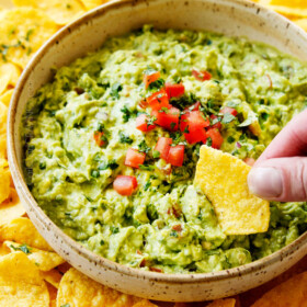 showing how tot make guacamole by tasting guacamole with a tortilla chip