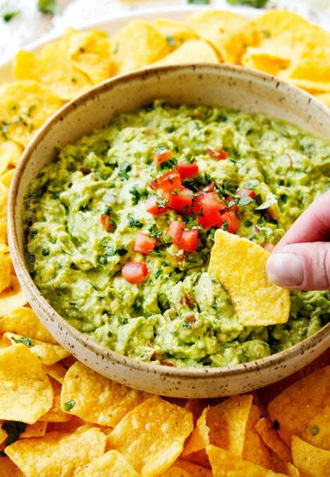 showing how tot make guacamole by tasting guacamole with a tortilla chip
