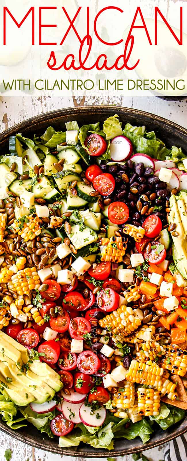 top view showing how to make Mexican Salad by adding tomatoes, corn, black beans, cucumbers and avocados to a wooden bowl