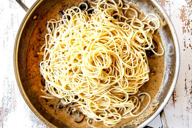 showing how to make mushroom pasta by adding spaghetti to mushroom pasta sauce in stainless steel skillet