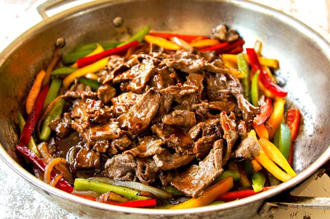 showing how to make Chinese Pepper Steak by adding cooked steak back to the stir fried bell peppers in the stainless steel pan