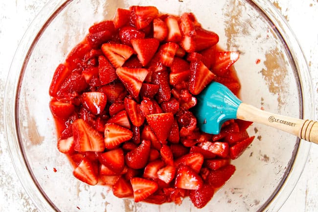 showing how to make Strawberry Shortcake by adding sliced strawberries to mashed strawberries in a glass bowl