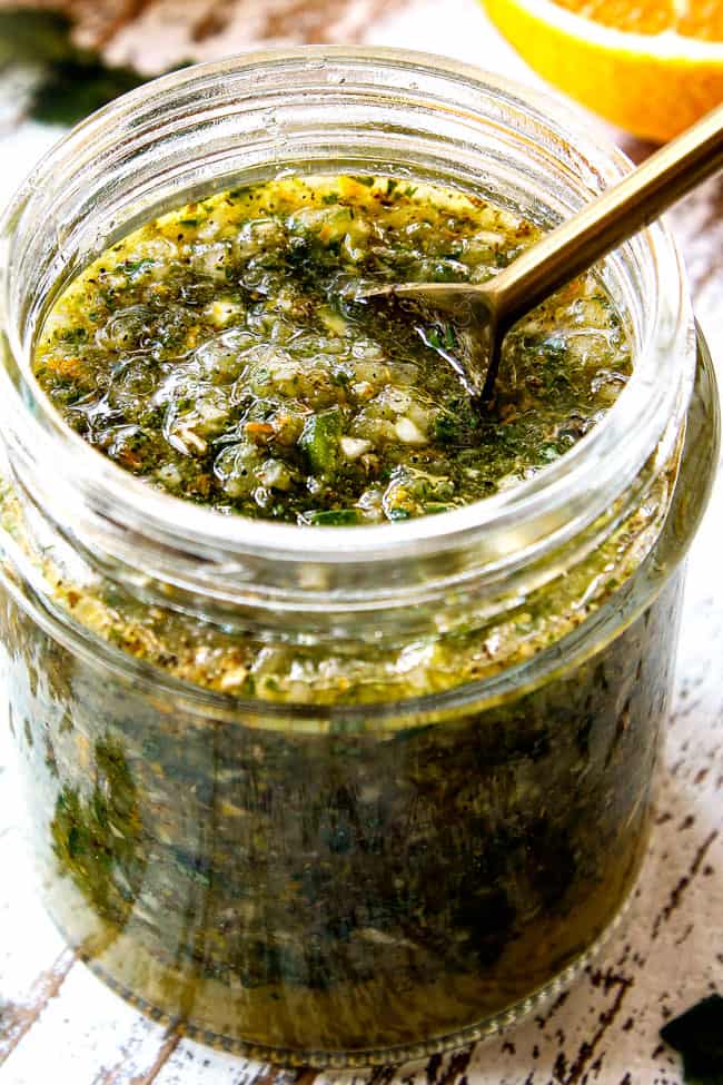 up close of mojo marinade in a glass jar with a spoon showing the texture