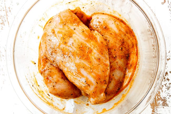 showing how to make Tuscan Chicken by marinating chicken breasts in a glass bowl