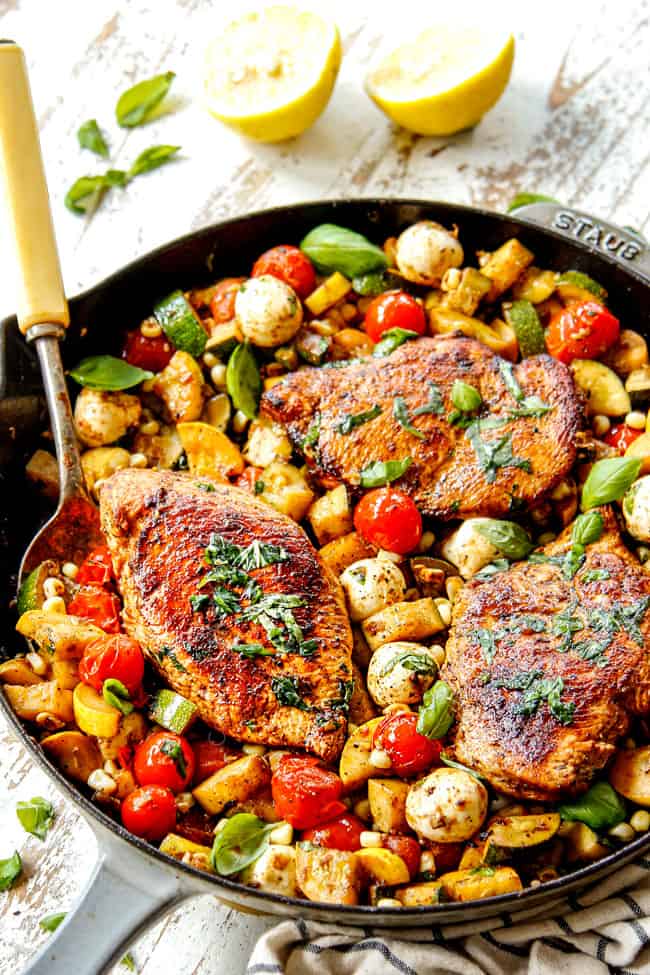serving Tuscan Chicken recipe with a big spoonful of veggies and chicken in  a cast iron skillet